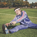 Ohne Sport abnehmen: Eine Frau dehnt sich, auf einer Wiese sitzend.