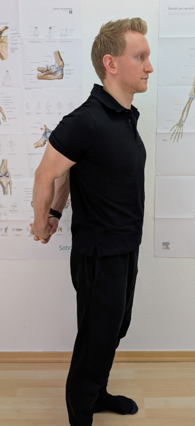 Brustdehnung: Stehend beide Arme nach hinten strecken.