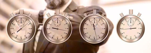 Im Hintergrund ein Mann im Anzug, der auf seine Uhr am Handgelenk schaut. Im Vordergrund sind vier Stoppuhren mit verschiedenen Zeiten.