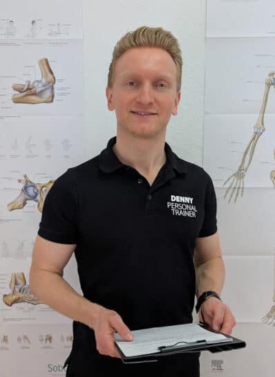 Denny Burkhardt steht aufrecht mit einem Klemmbrett in beiden Händen.