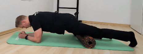 Denny ist im Unterarmstütz. Ein Bein liegt auf einer Faszienrollen.