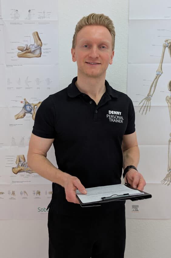 Denny Burkhardt steht aufrecht mit einem Klemmbrett in beiden Händen.