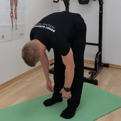 Rückenstrecker-Spannungstest: Denny steht vorgebeugt, mit den Händen Richtung Boden.