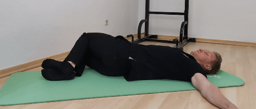 Übungen gegen Hohlkreuz: Denny liegt auf dem Rücken. Die Beine liegen angewinkelt zur rechten Seite.